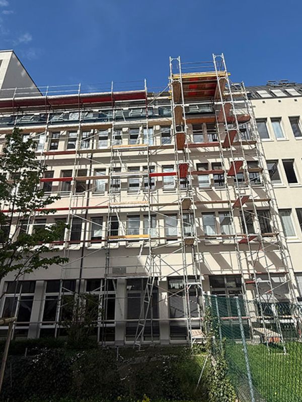 Fassendengerüst mit Dachfanggerüst und Lastturm bei einem Mehrparteienhaus in Innsbruck