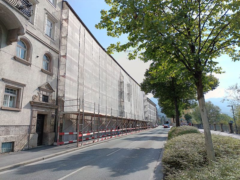 Baugerüst bei einem Mehrparteienhaus mit Passagentunnel und Gerüstverkleidung von Gerüstbau Mair in Tirol