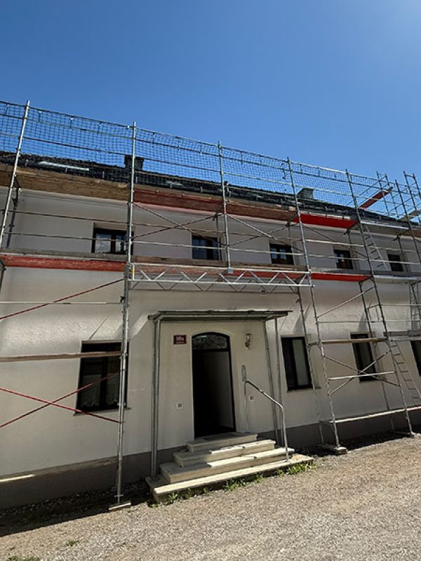 Fassadengerüst mit Überbauung bei der Tür und Dachfanggerüst eines Wohnhauses