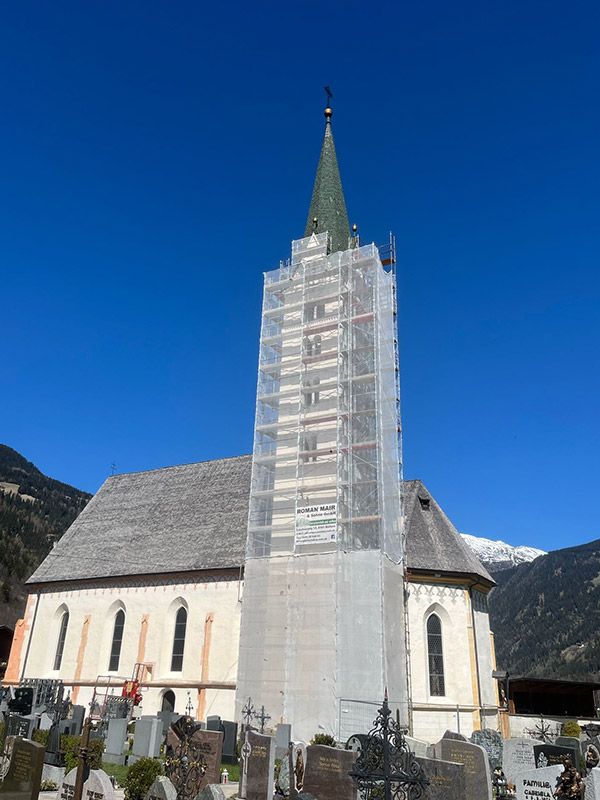 Eingerüsteter Kirchturm in Prutz mit Tiroler Bergpanorama